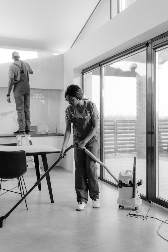 Mastering the First Impression: Your intriguing post title goes here Two professional cleaners working in a modern home interior, focusing on vacuuming and dusting.